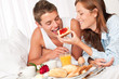 Happy man and woman having breakfast in bed together Happy man and woman having breakfast in bed together