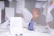 homme d'affaires se noyant dans un bureau pleins de papiers