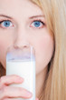 pretty blond girl with blue eyes drinking glass of milk