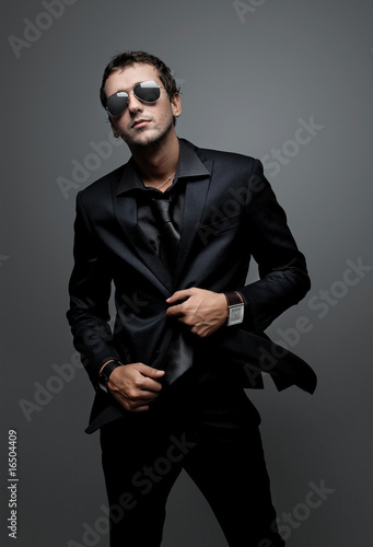 Photo: attractive young man wearing elegant black suit and sunglasses attractive young man wearing elegant black suit and sunglasses
