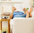 Young guy reading a novel while relaxing on a sofa