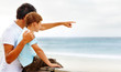 Foto: Father pointing towards the sea, showing something to his son Father pointing towards the sea, showing something to his son