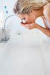 Young female drinking water from a basin tap