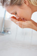 Young female washing her face at the wash basin