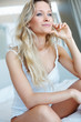Hot young woman lost in thought, sitting on the bed