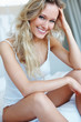 Foto: Happy woman sitting at the edge of the bed Happy woman sitting at the edge of the bed