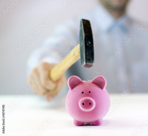 Photo: Pink piggy bank and hand with hammer Pink piggy bank and hand with hammer