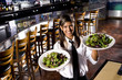 Hispanic waitress in restaurant serving salad plates