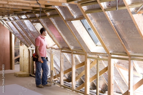 Foto: Electrician standing in attic under construction Electrician standing in attic under construction