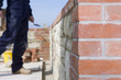Close up of brick wall with bricklayer in background