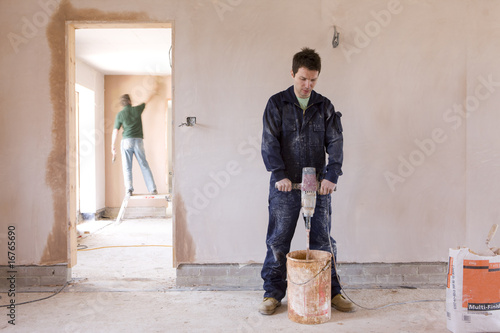 Photo: Man mixing plaster in house under construction Man mixing plaster in house under construction