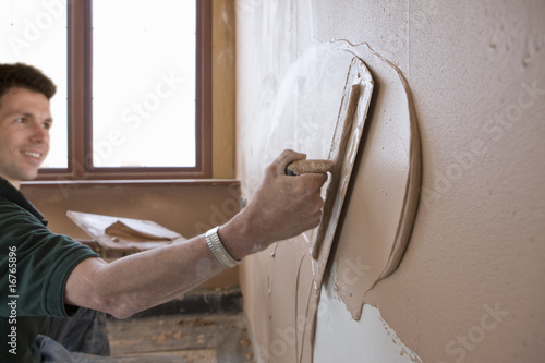 Photo: Man plastering wall with trowel Man plastering wall with trowel