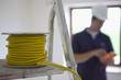 Close up of cable spool on ladder with electrician in background