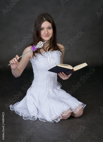 Photo: Girl - fairy in a white dress with magic wand and book Girl - fairy in a white dress with magic wand and book