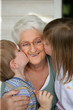 Foto: Enfants embrassant une femme senior souriante sur la joue Enfants embrassant une femme senior souriante sur la joue