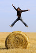 Photo: man jumping up on straw roll man jumping up on straw roll