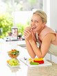 Happy woman in the kitchen making a salad