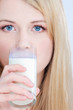 blond girl with blue eyes drinking glass of milk