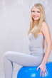 Pretty young blond hair girl seating on blue pilates ball