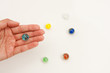 Hand Holding a Glass Marble with Others in the Background