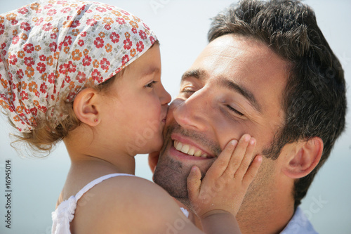 Photo: Portrait d'une petite fille embrassant un homme sur la joue Portrait d'une petite fille embrassant un homme sur la joue