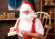 Photo: Santa Claus painting toy airplane in his workshop Santa Claus painting toy airplane in his workshop