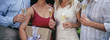 Young woman holding present, with friends drinking champagne, mid section