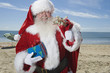 Father Christmas stands with his sack on a beach