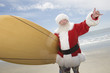 Foto: Father Christmas stands with a surfboard at the beach Father Christmas stands with a surfboard at the beach
