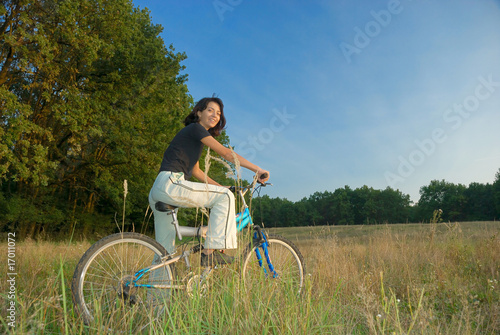 Photo: young female riding a bike in nature young female riding a bike in nature