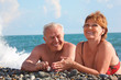 happy aged pair lie on pebble beach