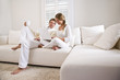 Images : Father and teen daughter on white living room sofa using laptop