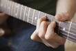 Young man playes chord on guitar