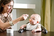 Photo: Mother feeding six month old baby solid food Mother feeding six month old baby solid food