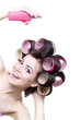 Laughting girl with colorful hair-curlers and hair spray