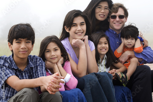 Photo: Multiracial family sitting on beach Multiracial family sitting on beach