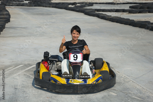 Photo: prety brunette driving a kart on karting circuit prety brunette driving a kart on karting circuit