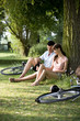 A young couple sitting under a tree using a mobile phone