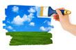 Hand with paintbrush drawing landscape