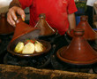 Market cook holding a cover of a tajine dish (traditional casser