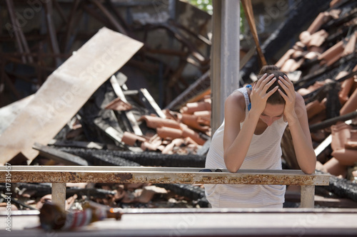 Photo: sad woman and destroyed house sad woman and destroyed house
