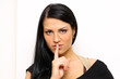 woman making hush sign standing indoors