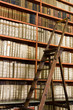 Shelves with old books in the library and wooden stepladder Shelves with old books in the library and wooden stepladder