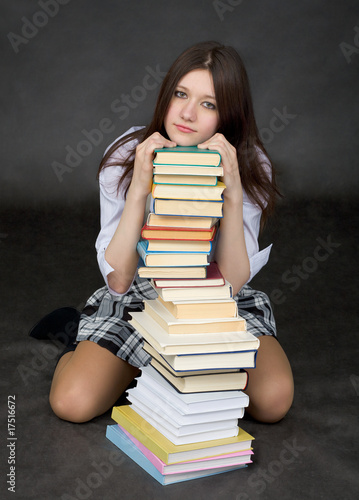Photo: Girl sits on a floor embracing big pile of books Girl sits on a floor embracing big pile of books