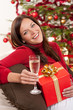 Smiling woman with Christmas present and glass of champagne