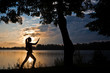 Silhouette of woman doing yoga exercise on the riverside