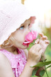 Little girl smelling a pink rose