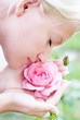 Young pretty woman enjoys a smell of  pink rose