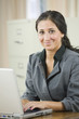 Foto: Young woman with laptop in her office. Young woman with laptop in her office.