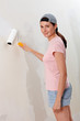 Young woman decorate wall, paint droplet in her face